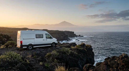 Campervan parked on remote volcanic terrain with dramatic Tenerife coastline and Mount Teide in background at golden hour