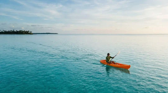 Kayaker paddling on calm turquoise water during surface interval after scuba diving